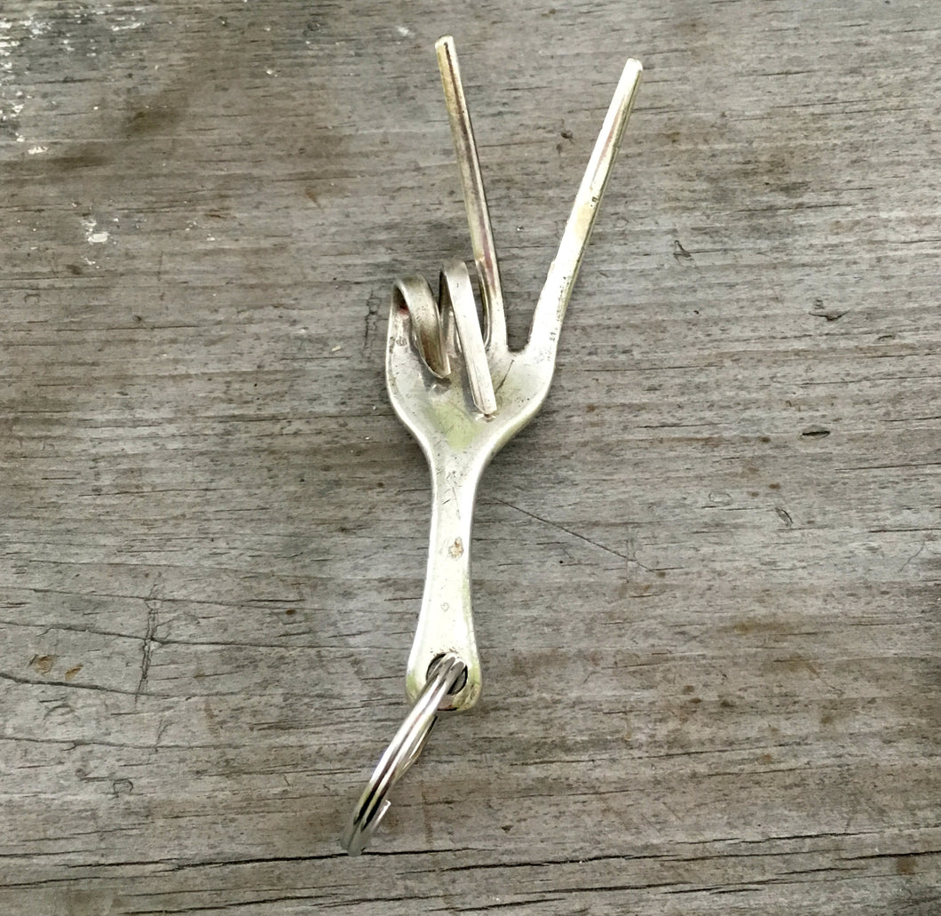 Key chain upcycled from a fork into the shape of a hand give the peace sign hand gesture