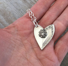 Upcycled silverware spoon heart necklace shown in hand for scalce