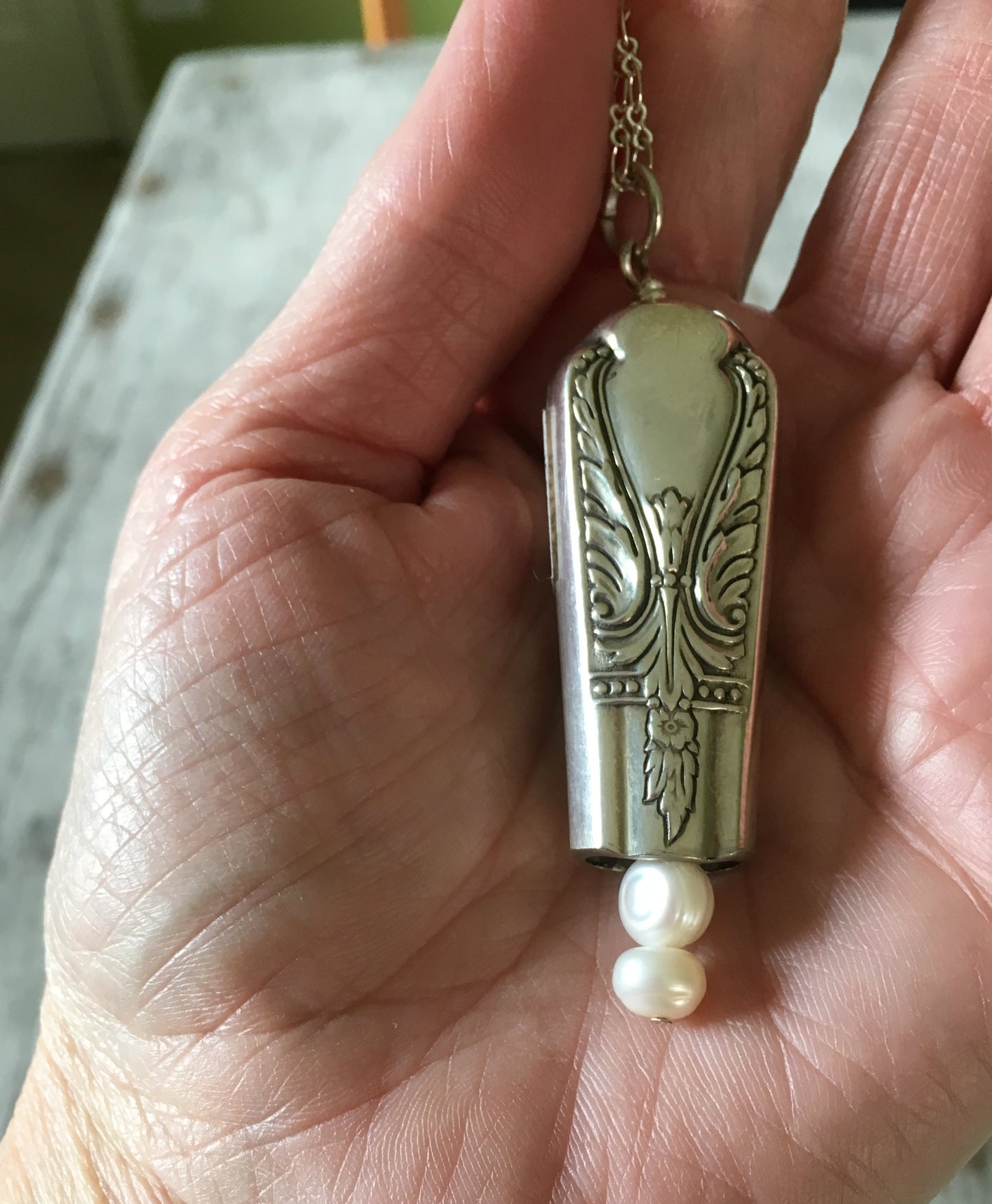 upcycled Knife Bell Necklace from Avalon Cabin Pattern shown in hand for size and scale