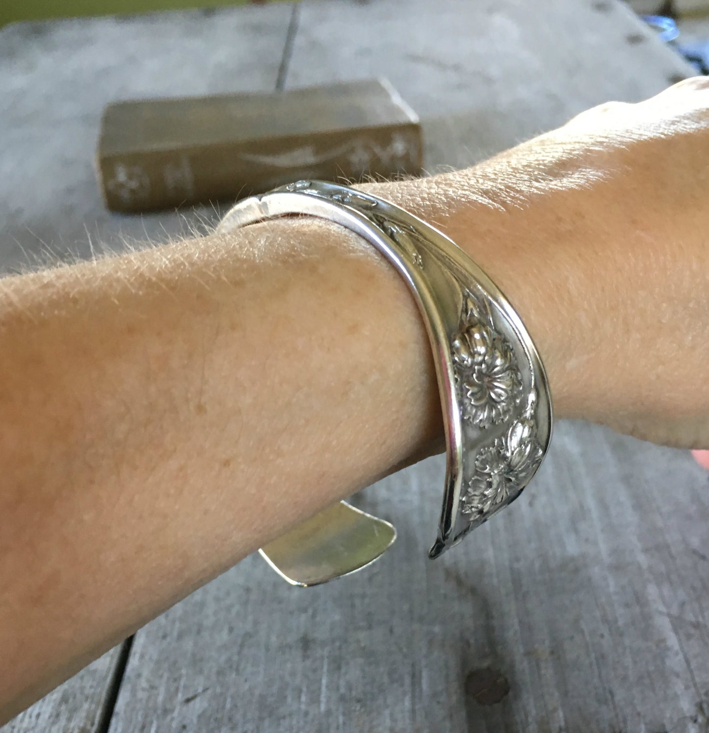 Carnation pattern spoon cuff bracelet shown on a wrist - handcrafted from upcycled vintage silverware - Laughing Frog Studio