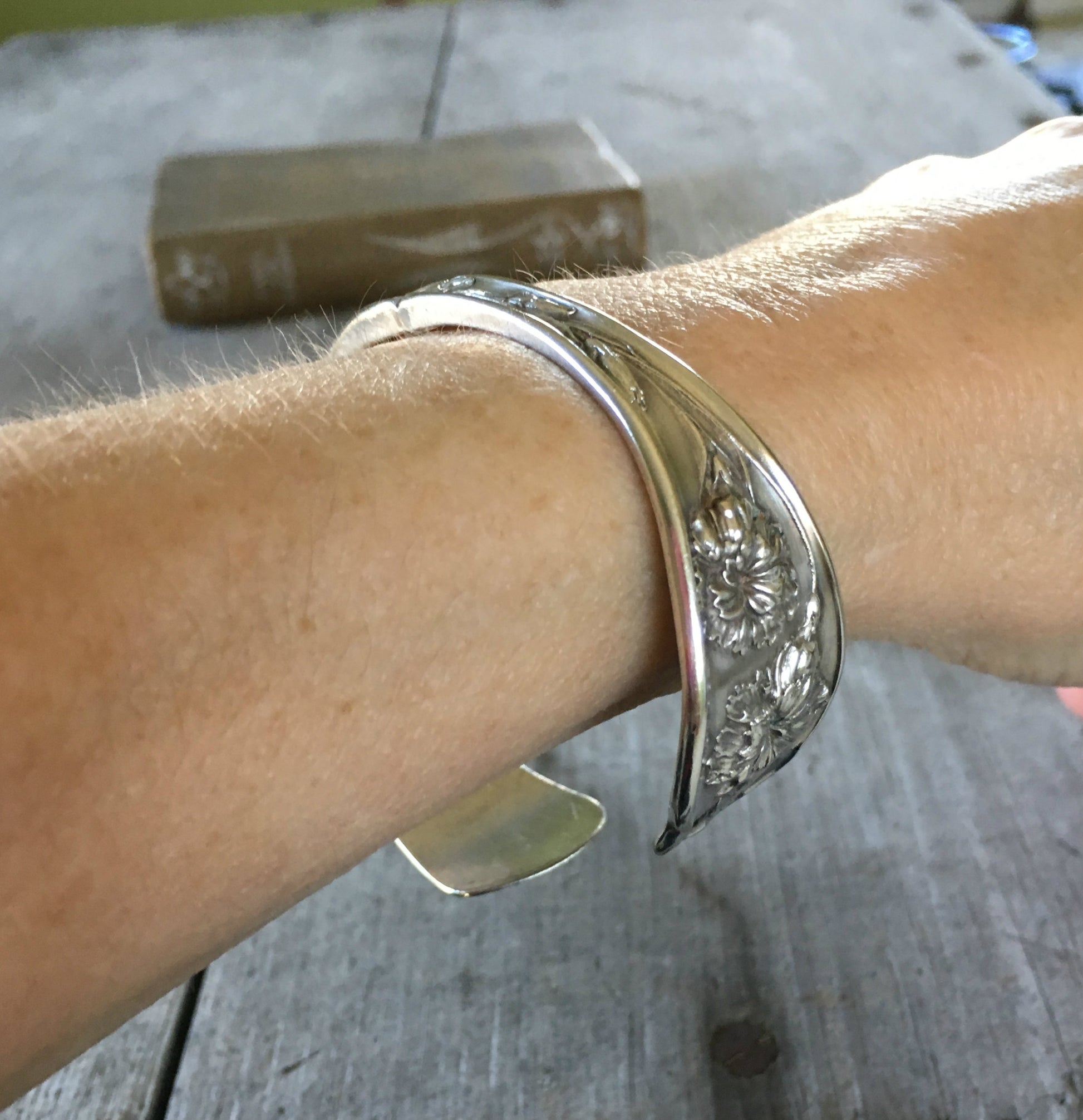 Carnation pattern spoon cuff bracelet shown on a wrist - handcrafted from upcycled vintage silverware - Laughing Frog Studio