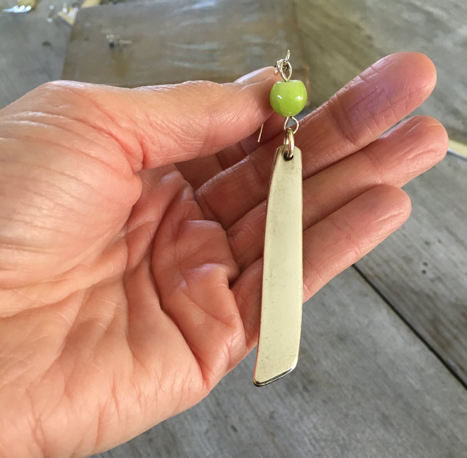 South Seas Spoon Handle Earrings shown with hand for size scale