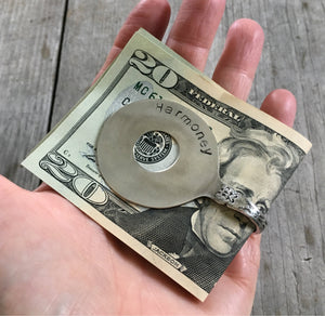 Spoon money clip shaped like banjo shown in hand for visual scale
