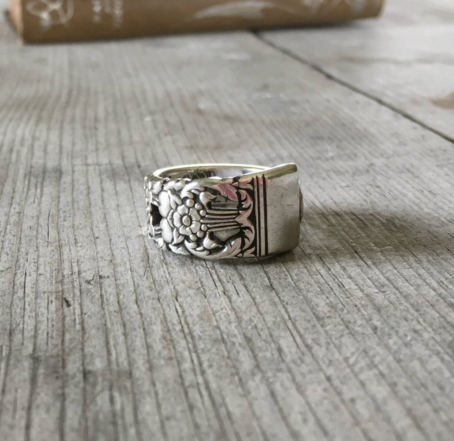 Close-up of CORONATION pattern spoon ring showing ornate vintage silverware detail