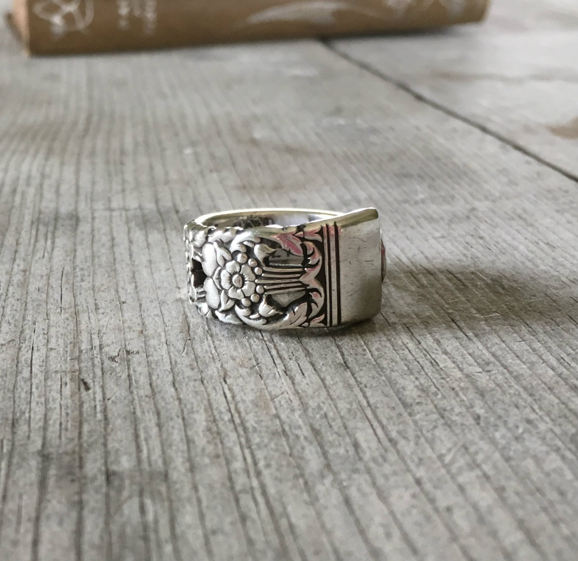 Close-up of CORONATION pattern spoon ring showing ornate vintage silverware detail