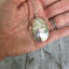 Upcycled Spoon Handmade into a Ladybug Necklace Shown in hand for scale