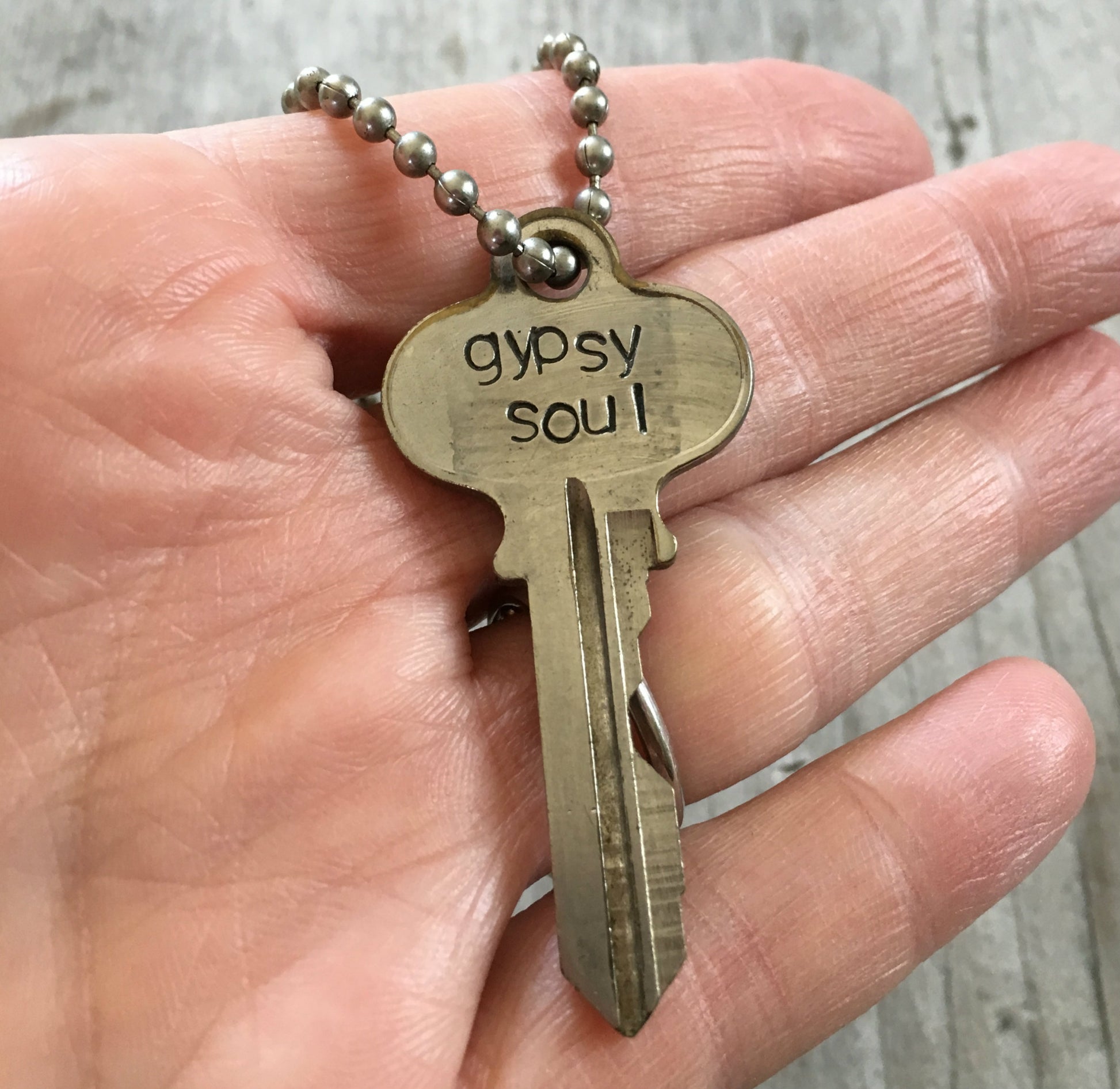 key necklace HAND stamped with gypsy soul shown in hand for scale