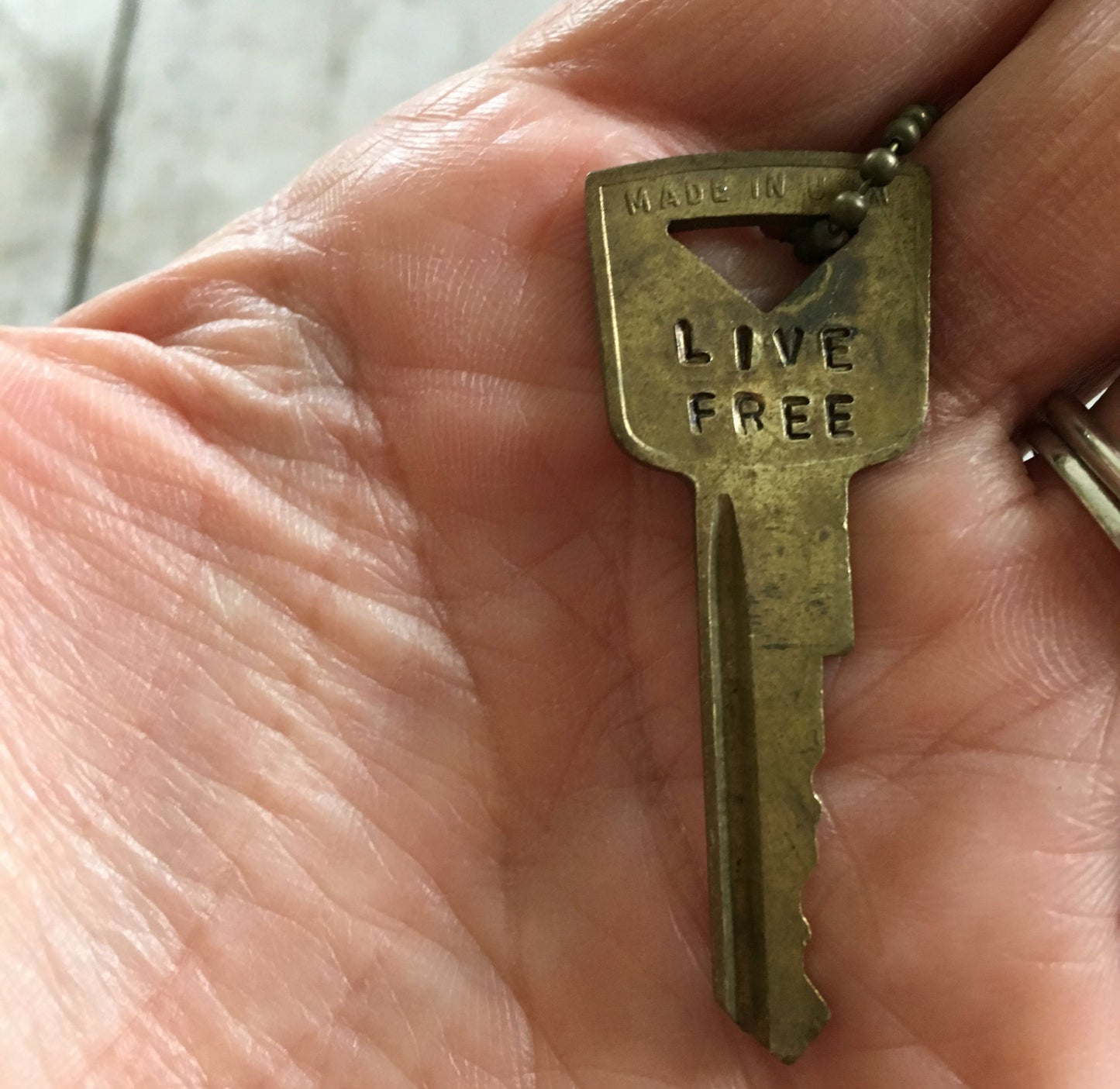 Close up of Vintage Gold Tone Hand Stamped Key LIVE FREE on ball chain
