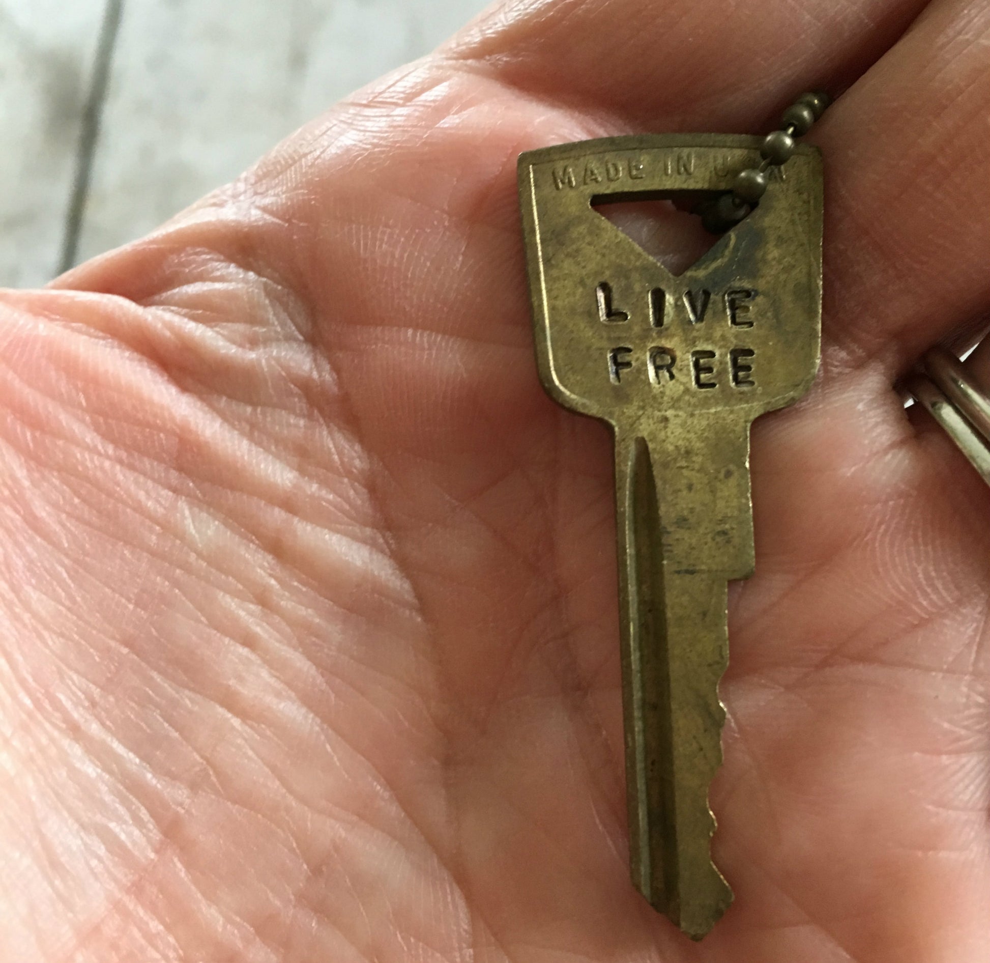 Close up of Vintage Gold Tone Hand Stamped Key LIVE FREE on ball chain