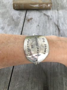 Hand stamped spoon bracelet about creativity shown on model's arm
