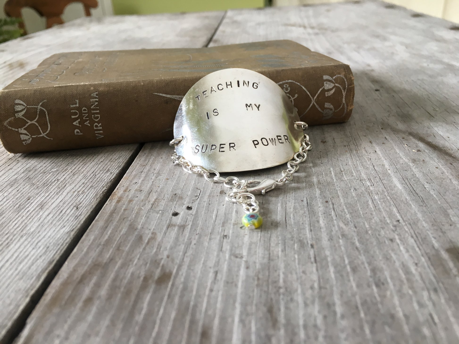 Wide View of hand-stamped teacher superpower lettering and sunny yellow millefiori bead on flattened vintage spoon bowl bracelet