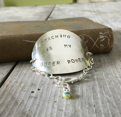 Hand-stamped vintage spoon bracelet with 'Teaching Is My Super Power' message and bright yellow millefiori glass bead