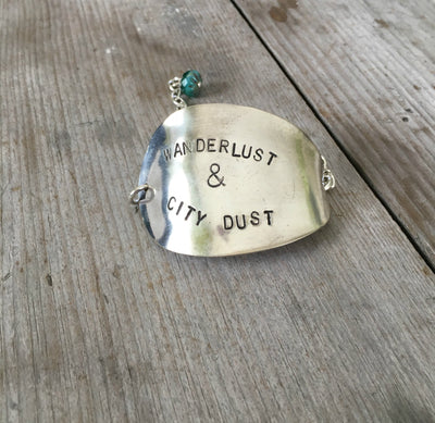 Hand-stamped vintage spoon bracelet with 'Wanderlust & City Dust' message and turquoise glass bead accent
