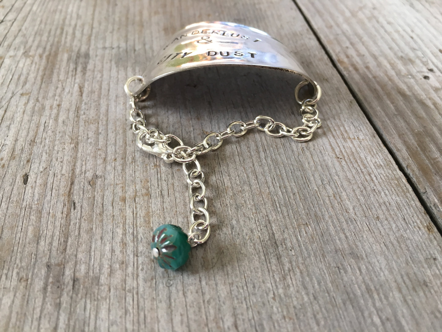 Hand-stamped vintage spoon bracelet with 'Wanderlust & City Dust' message and turquoise glass bead accent