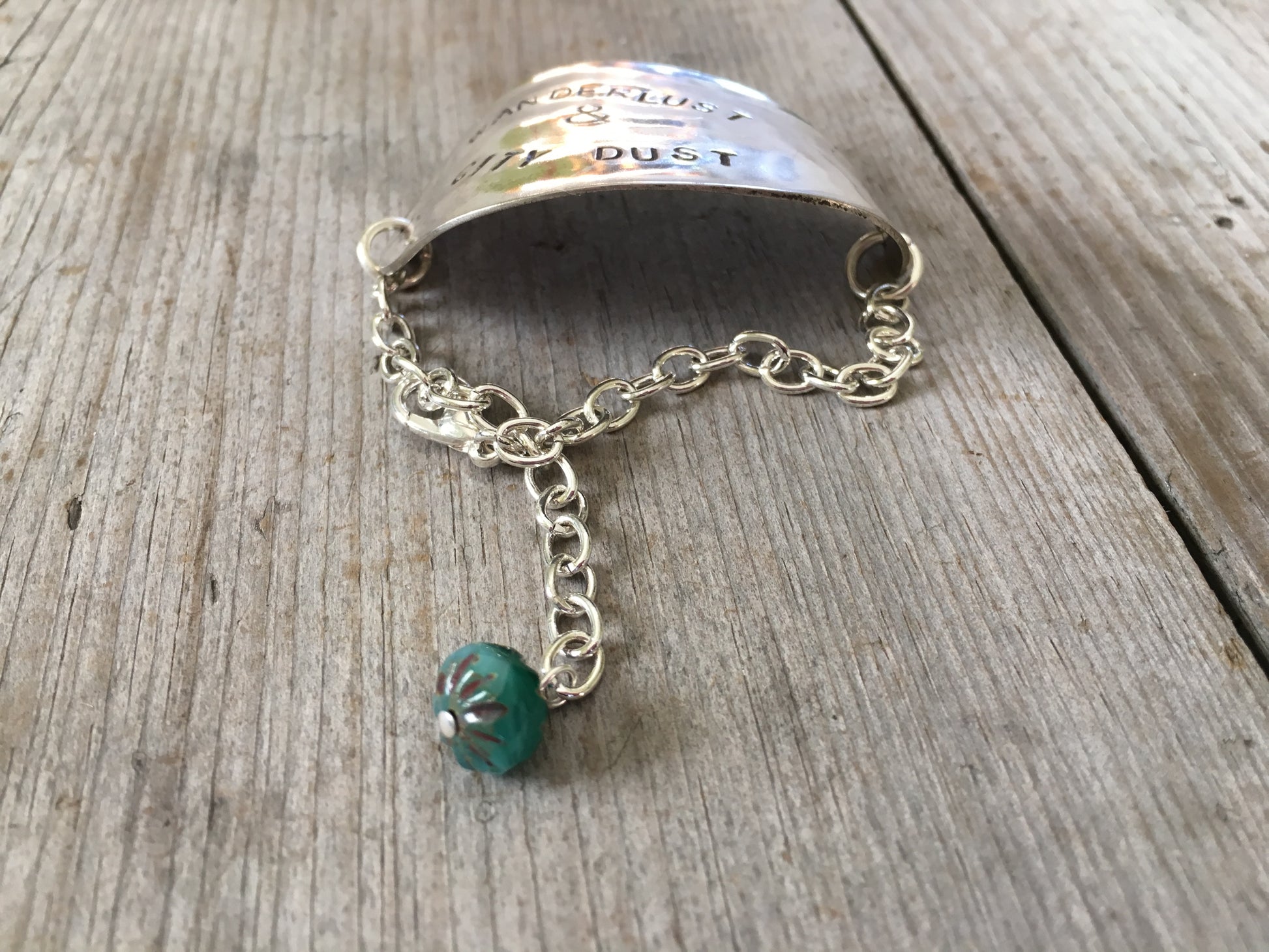 Hand-stamped vintage spoon bracelet with 'Wanderlust & City Dust' message and turquoise glass bead accent
