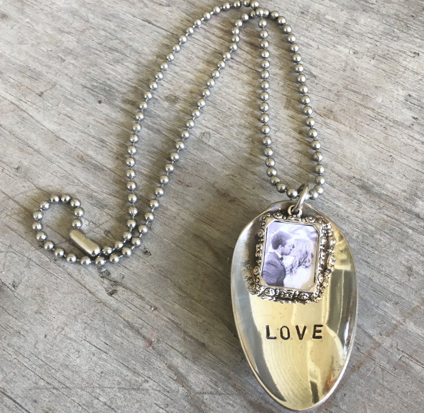 Close-up detail of LOVE stamped spoon pendant with pewter frame for photo, eco-friendly upcycled vintage silverware