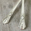 Close up of hand stamped words his and hers on Avalon vintage silverplate forks for wedding cake table