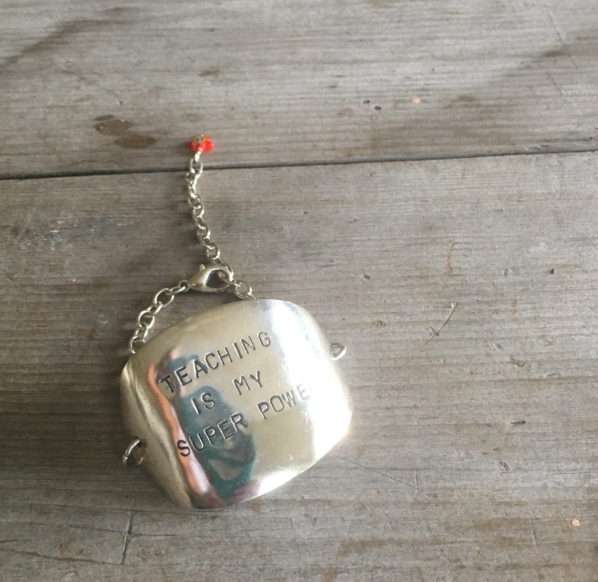 Stamped spoon bracelet with Teaching is my super power with red millifiori glass bead