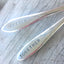 Close up of the handles of Handstamped mismatched set wedding cake forks that read better together