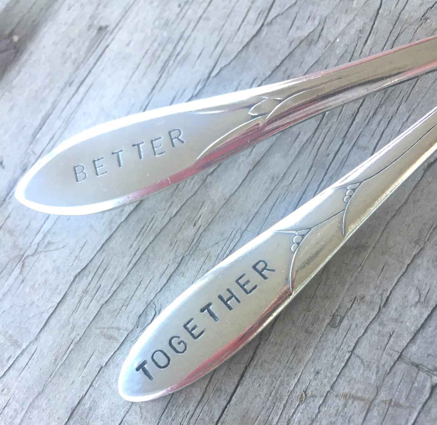 Close up of the handles of Handstamped mismatched set wedding cake forks that read better together