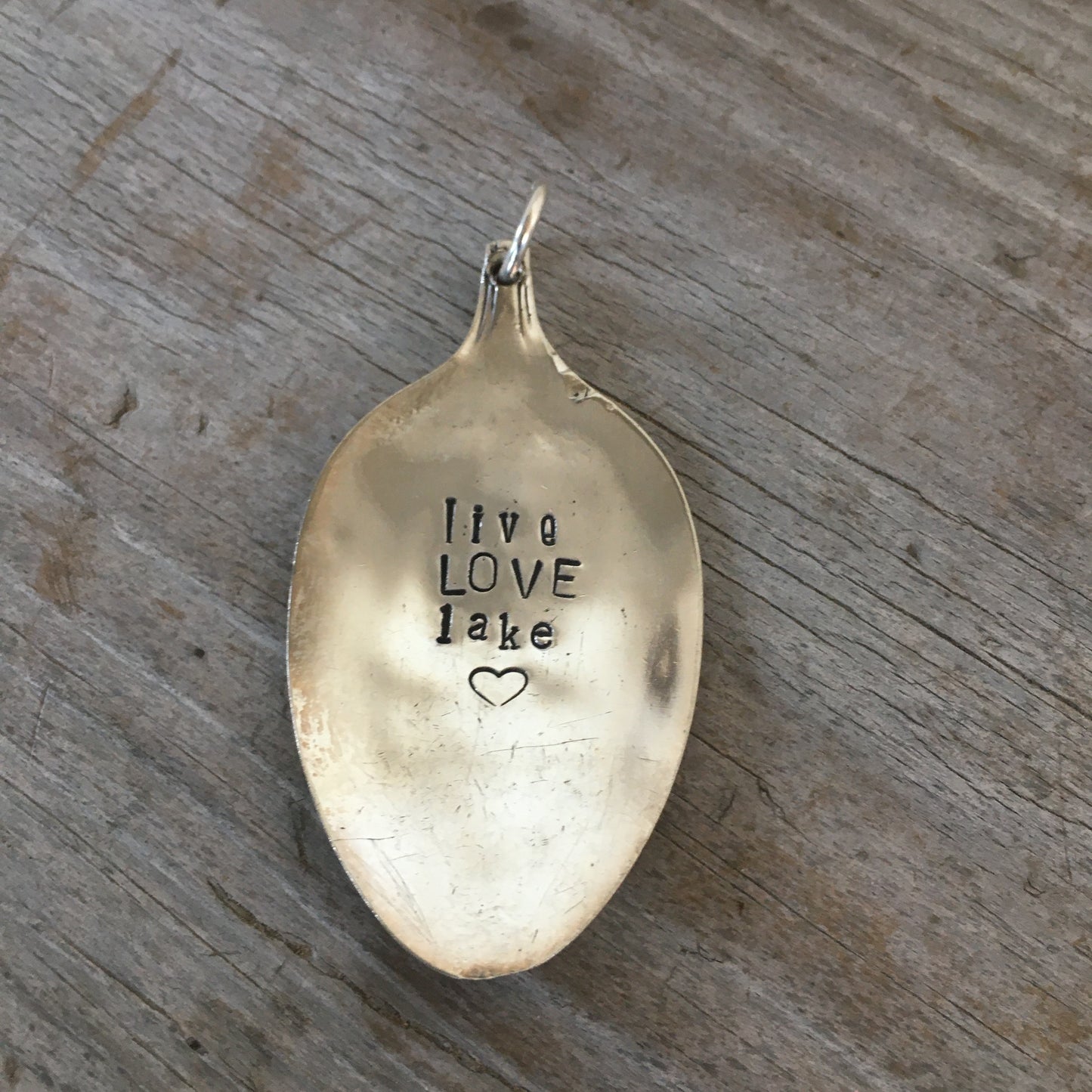 Close-up of LIVE LOVE LAKE stamped spoon pendant on vintage ball chain, soulful lake-themed design