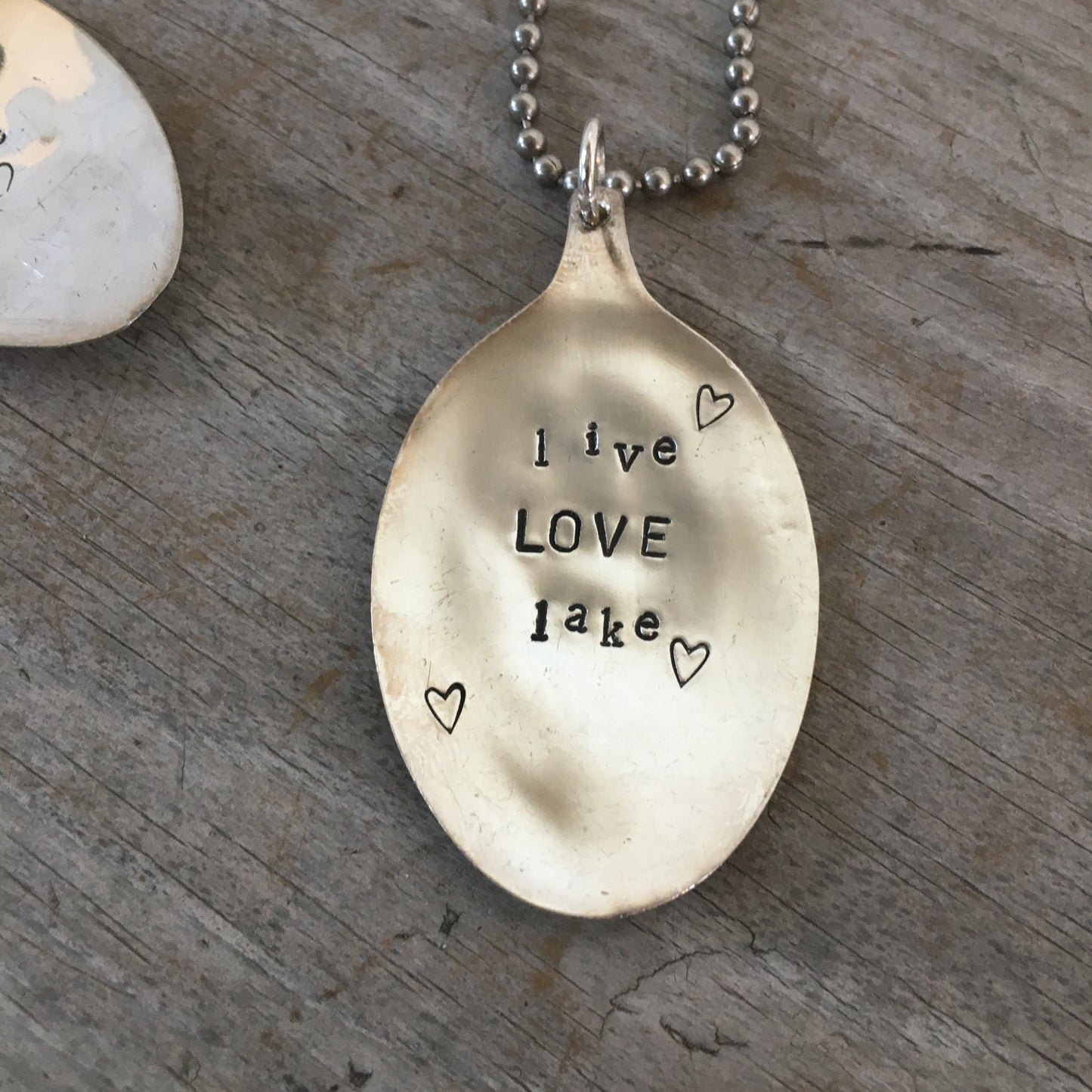 Detail of LIVE LOVE LAKE hand-stamped spoon pendant, soulful lake-themed design